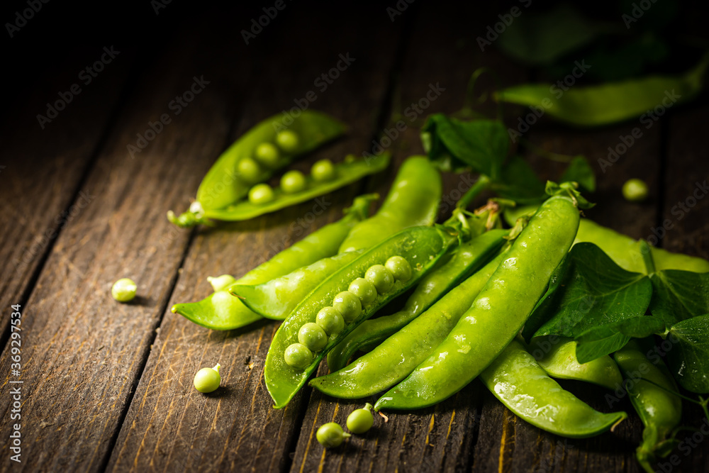 Pods of green peas on a old wooden background close up, soft focus Pods of green peas on a old wooden background close up, soft focus