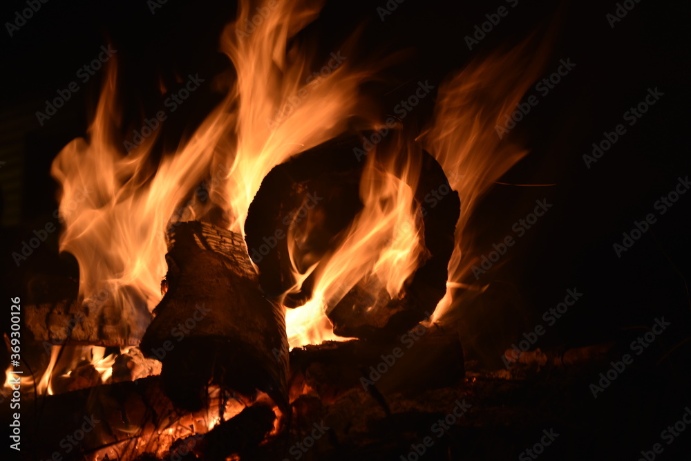 Log on fire in a bonfire with flames surrounding it 