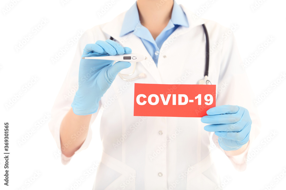 Doctor holding thermometer and paper with text Covid-19 Doctor holding thermometer and paper with text Covid-19
