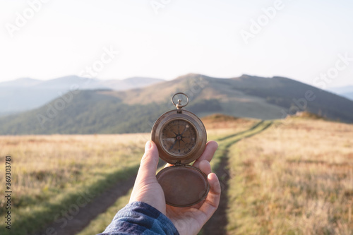 Man with old metal compass in hand on mountains road. Travel concept. Landscape photography