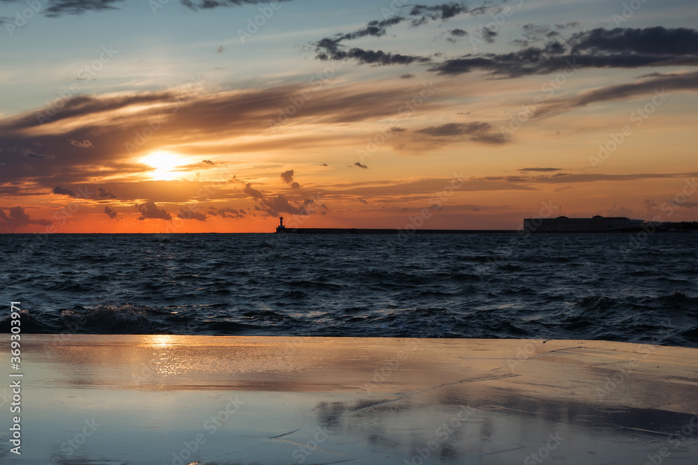 Obraz premium Beautiful sunset on the embankment of Sevastopol (Crimea). The sun sets in the sea. Very beautiful seascape, view of the sea, waves and sky with clouds.