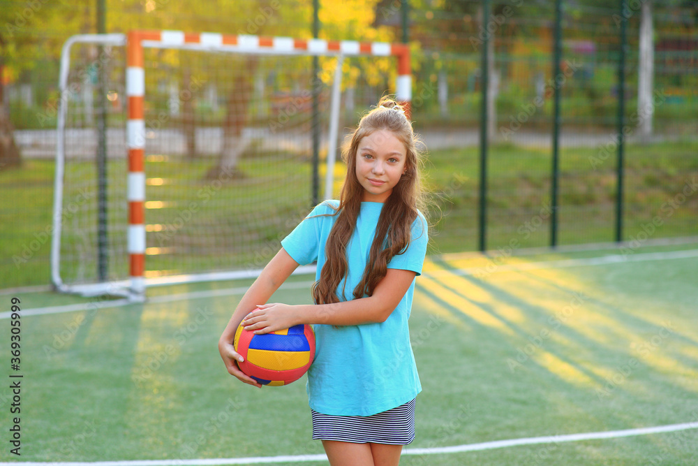 Girl with a ball in his hands on the football field.