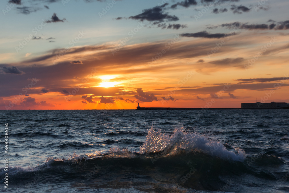 Fototapeta premium Beautiful sunset on the embankment of Sevastopol (Crimea). The sun sets in the sea. Very beautiful seascape, view of the sea, waves and sky with clouds.