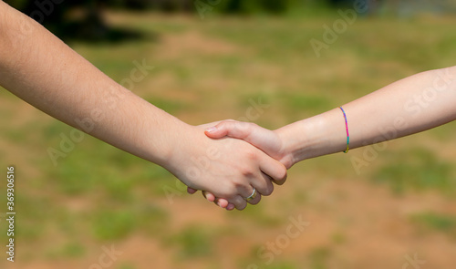 Stretta di mano fra ragazze all'aria aperta di un parco. Incontro cordiale © Eroyka