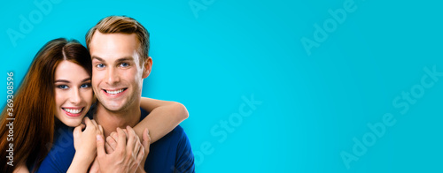 Smiling young amorous couple. Portrait image of embracing caucasian models at happy in love studio concept isolated against aqua blue marine color background. Man and woman posing together, copy space