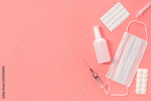 Medical kit. Syringe, mask, tablets and sanitizer on a pink background. Means for the prevention and treatment of coronavirus. Covid-19 concept.