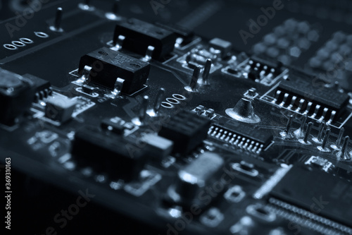 Fragment and components of a motherboard (PCB) of computer technology with many elements. Macro photography of processors and transistors. IT industry background