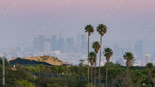Timelapse day to night transition of downtown Los Angeles skyline thru palm trees photo