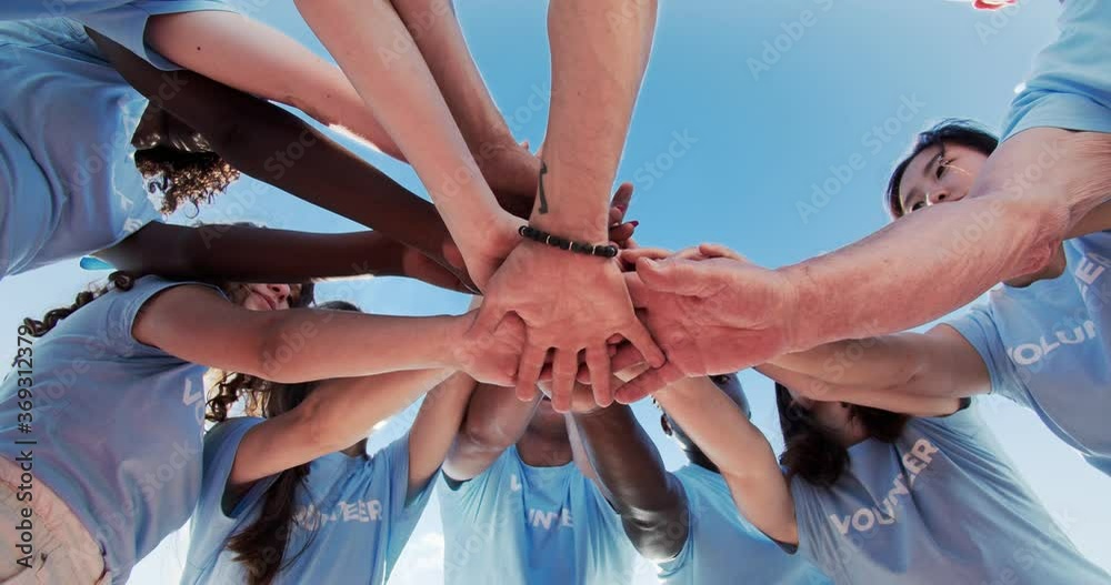 Joyful multiracial group of volunteers helping to protect natural environment. Cheerful activists of different ages cheering and stacking hands. Team building, teamwork, friendship concept.