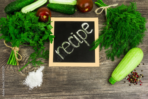 Vegetables: tomato, cucumber, courgette, dill, parsley on wooden background. Recipe table cuisine