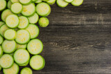 Slices of fresh green squash, zucchini, courgette  on wooden background