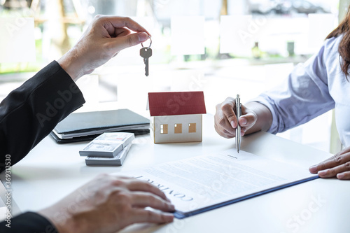 Estate agent giving house keys to client after signing agreement contract