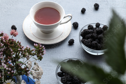 Blackberries with a Cup of tea on a gray background, bokeh