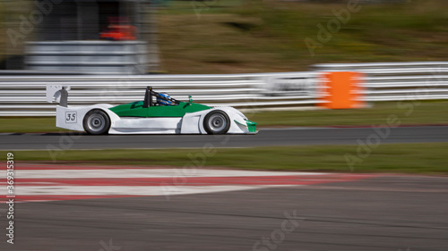A panning shot of a white and green racing car as it circuits a track.