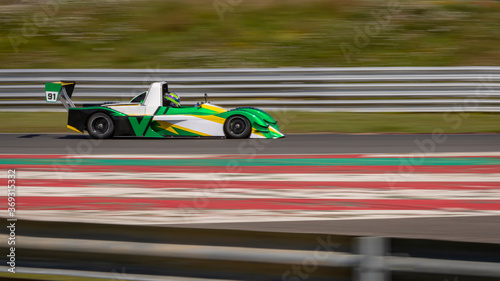 A panning shot of a white and green racing car as it circuits a track.