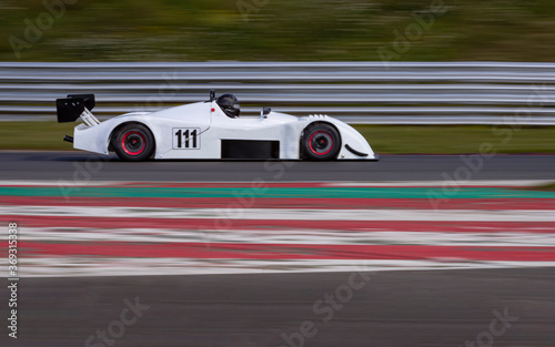 A panning shot of a white racing car as it circuits a track.