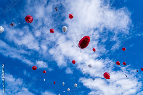 Many released flying balloons with card in blue sky - Wedding Balloons