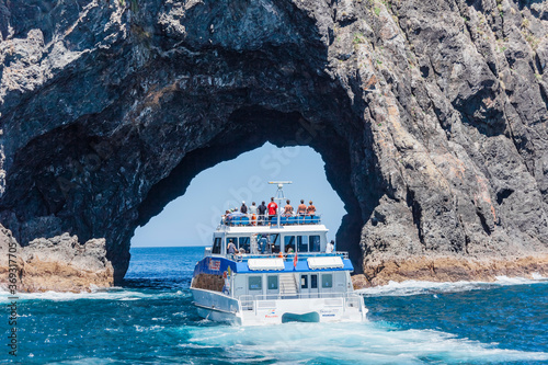 Tour boat entering The Hole in the Rock in Bay of Islands, New Zealand photo