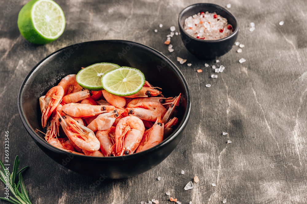 Top view of bowl with boiled shrimps with lime in black bowl on dark background. Top view of bowl with boiled shrimps with lime in black bowl on dark background.