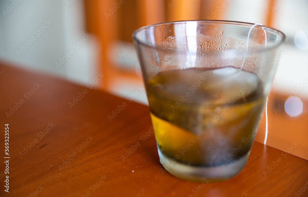 Close-up image of a cold herbal tea: the glass is covered with condensation. The sachet is infused in the glass. Close-up image of a cold herbal tea: the glass is covered with condensation. The sachet is infused in the glass.
