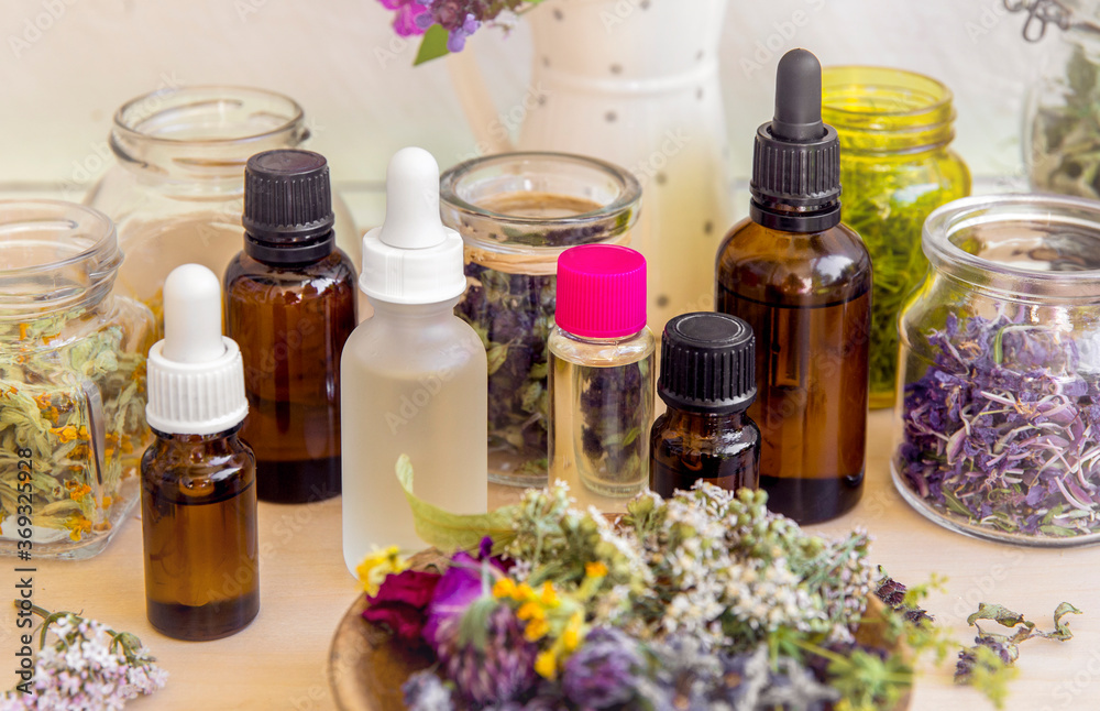 Lot of different aromatherapy oil bottles on table, decorated with wild dried flowers and plants. Lifestyle composition. Lot of different aromatherapy oil bottles on table, decorated with wild dried flowers and plants. Lifestyle composition.