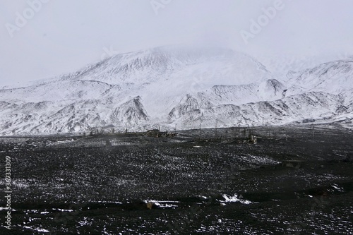Antarctica, deception island, ruin in storm, snow on volcanic black stone