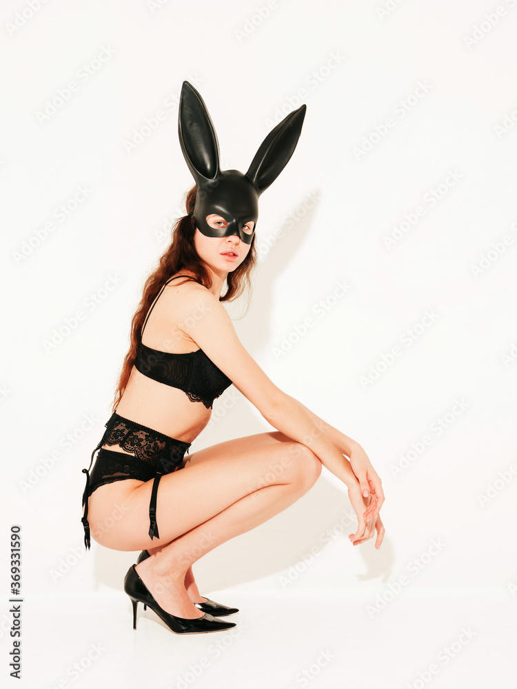 Beautiful sexy woman wearing carnival black mask of Easter bunny rabbit.Hot blonde girl posing near white wall in studio. Seductive model in nice lingerie Beautiful sexy woman wearing carnival black mask of Easter bunny rabbit.Hot blonde girl posing near white wall in studio. Seductive model in nice lingerie