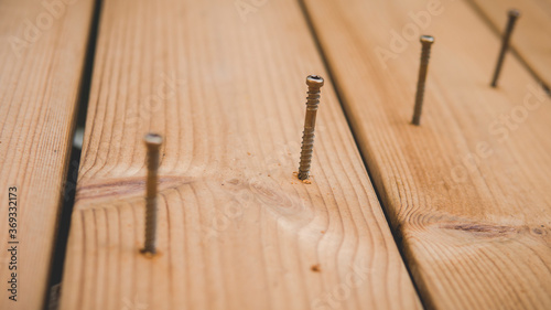 row of metal screws on a wooden terrace