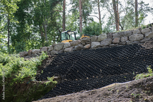 Security concept. Strengthening the mountain slope with construction equipment, artificial mesh, geogrids that prevent rockfalls and landslides of mobile and loose soils. photo