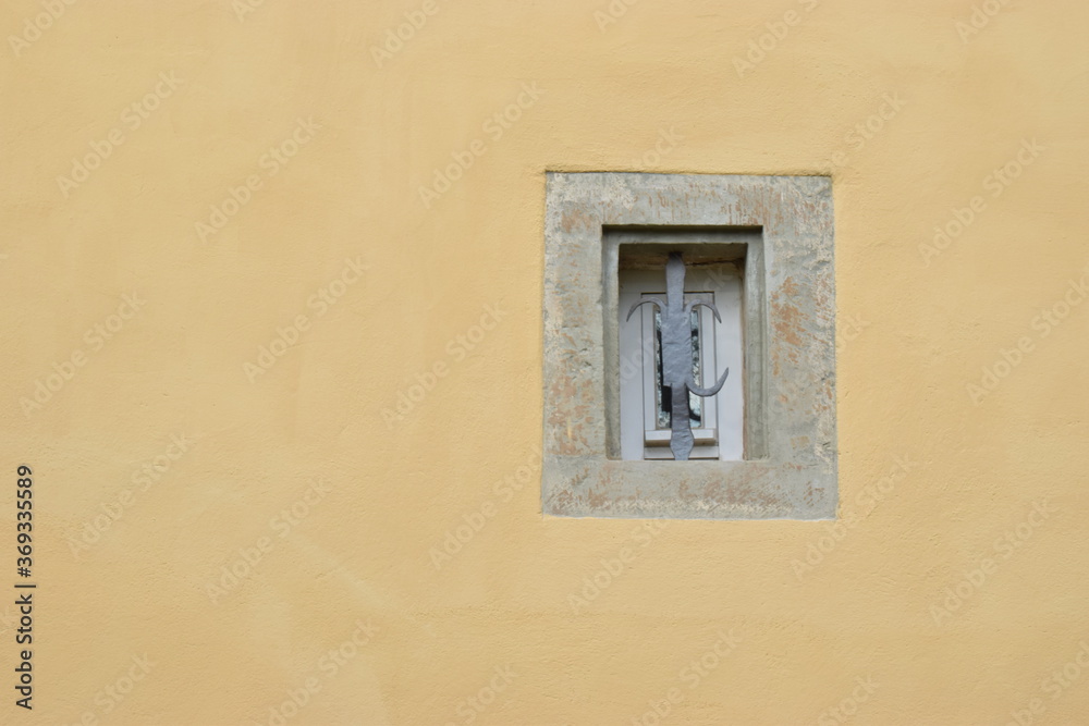 Sandsteinumrandetes Fenster in einer lehmgelben Putzfassade Sandsteinumrandetes Fenster in einer lehmgelben Putzfassade