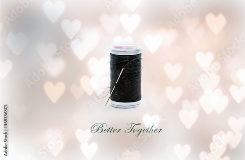 A needle and black thread for sewing against heart bokeh background representing better together concept