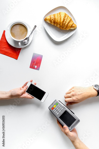 Coffee, croissant and card payment on white background top view