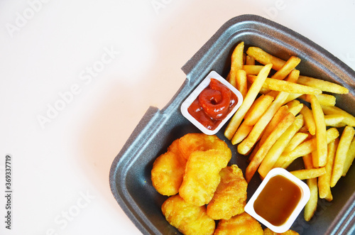 Yummy French fries, chicken Nuggets, sauce, paper bag, white background. Binge eating. food delivery photo