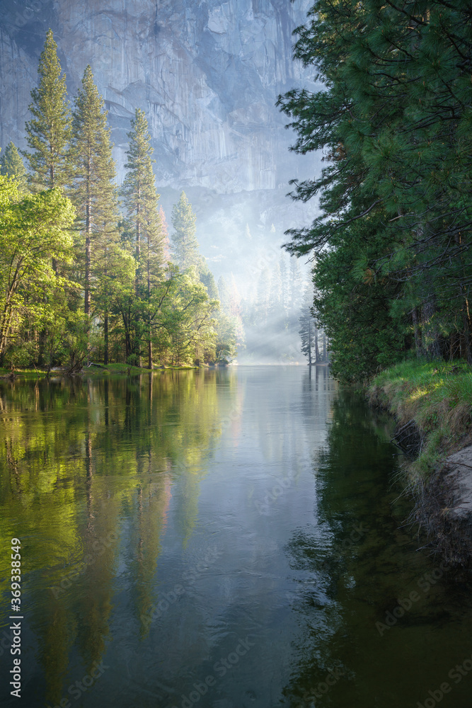 sunbeams on a foggy morning over merced river in yosemite national park