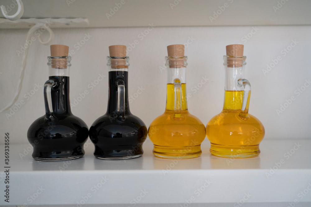A small glass bottle of pomegranate sour sauce with extra virgin olive oil bottles isolated on white background under natural light. A small glass bottle of pomegranate sour sauce with extra virgin olive oil bottles isolated on white background under natural light.