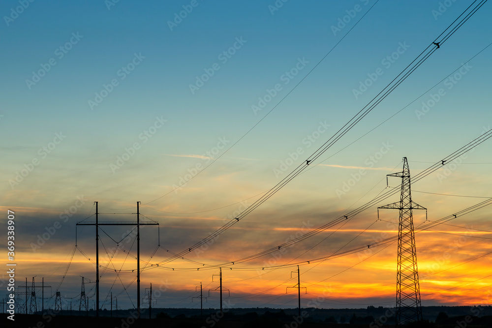 High-voltage power lines at sunset by the road. Horizontal