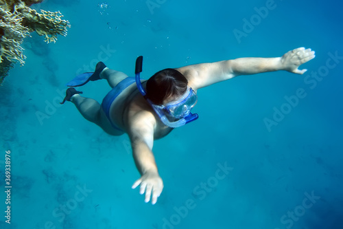 scuba diver coral with mask snorkel and flippers rises to the surface
