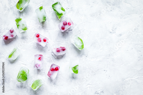 frozen red berries in ice cubes on stone background space for text top view