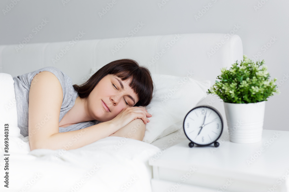 beautiful woman sleeping in bed at home, alarm clock on bedside table beautiful woman sleeping in bed at home, alarm clock on bedside table