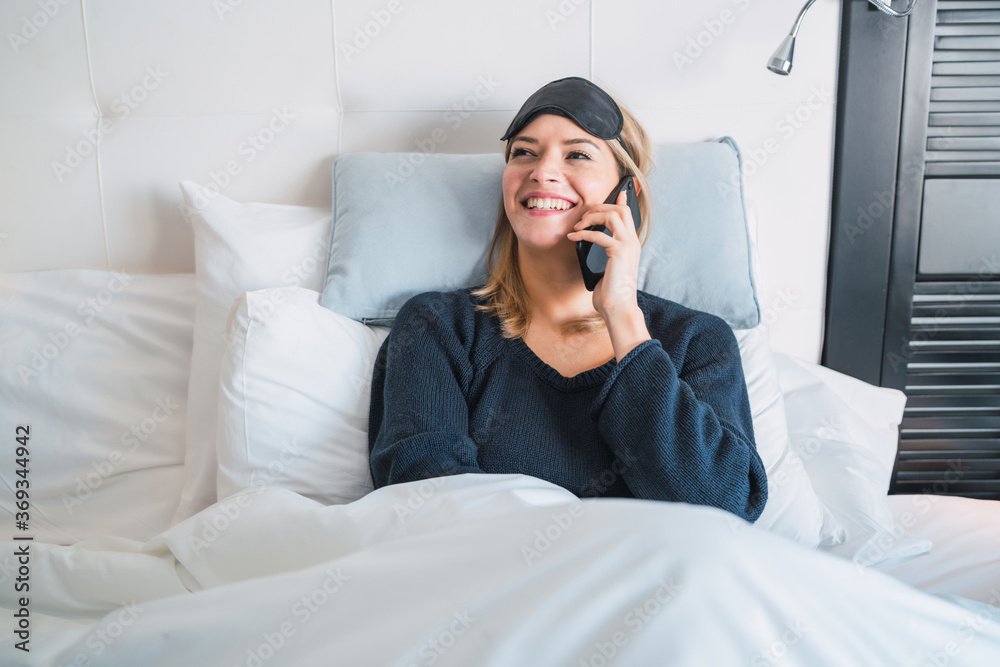 Young woman talking on the phone while laying on bed. Young woman talking on the phone while laying on bed.