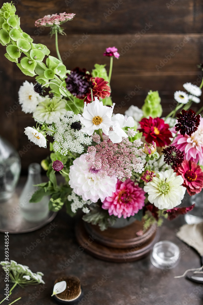 Fototapeta premium Big beautiful bouquet. Flower arrangement on a brown background. A wide variety of farm flowers. English floristry. Dahlias, zinnias, moluchella and scabiosa.