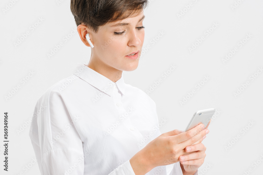 a young girl uses wireless headphones for a video call. white background in studio. online business meeting concept a young girl uses wireless headphones for a video call. white background in studio. online business meeting concept