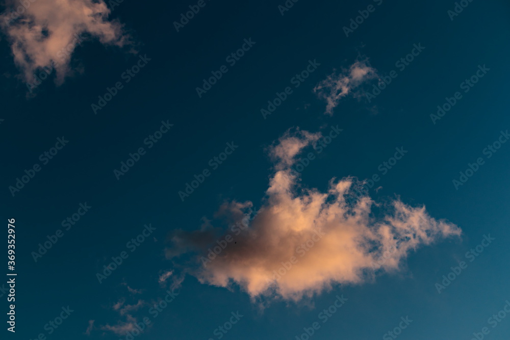 tuft of white cloud, backlit by sunlight, floating under a blue sky. tuft of white cloud, backlit by sunlight, floating under a blue sky.