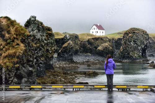 Iceland nature landscape on Arnarstapi Snaefellsnes. Travel photo of woman tourist looking at view of dramatic coast and ocean on West Iceland. From Arnarstapi harbour, Iceland. photo