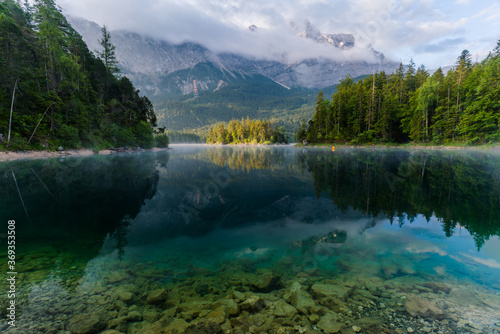 Beautiful and cloudy Summer sunrise on the Eibsee lake in German Alps, southwest of Garmisch-Partenkirchen below the Zugspitze in the Wetterstein Mountains in Bavaria