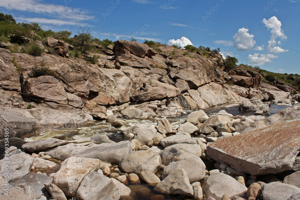 Natural rock texture. View of the river flowing along the stone valley in the mountains. Many rocks in the river bed and shore. 