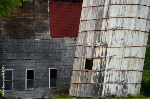 leaning silo with old barn background