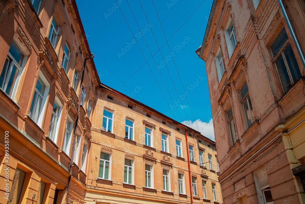 old city narrow street building walls foreshortening from below with vivid blue sky background in clear weather day