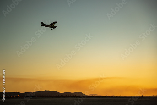 Private plane about to land in El Mirage dry lakebed in California during a sunset
