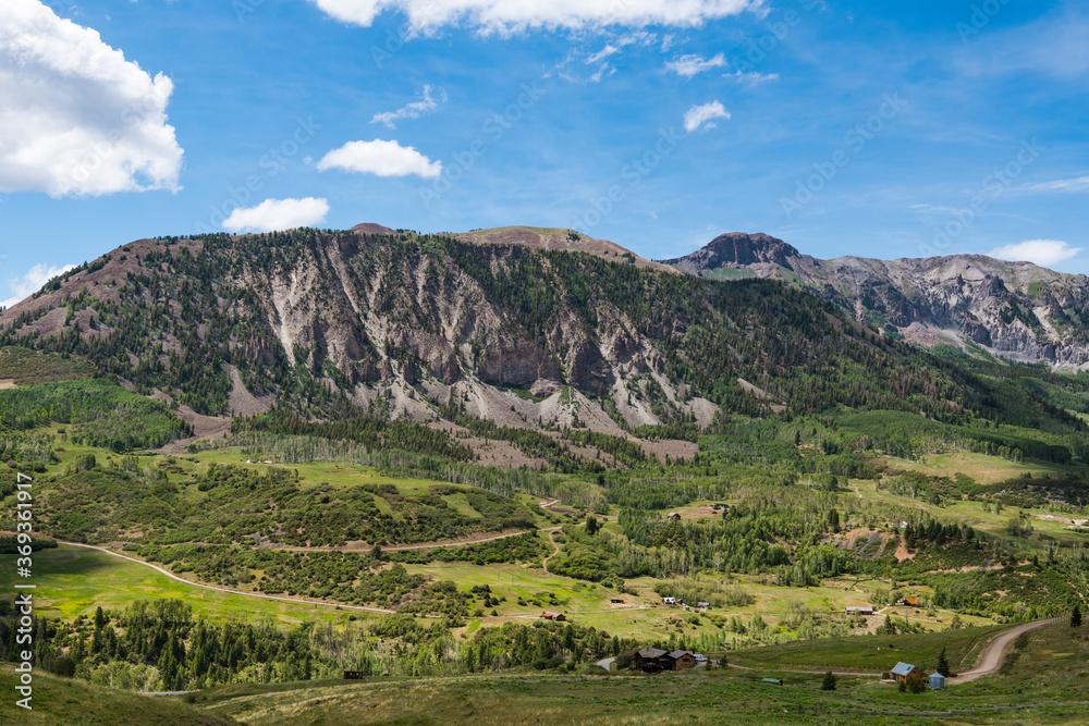 Rugged landscape of mountains, green fields, ranches, and buildings along Last Dollar Road near Telluride, Colorado